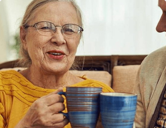 Elderly couple sitting together drinking hot drink