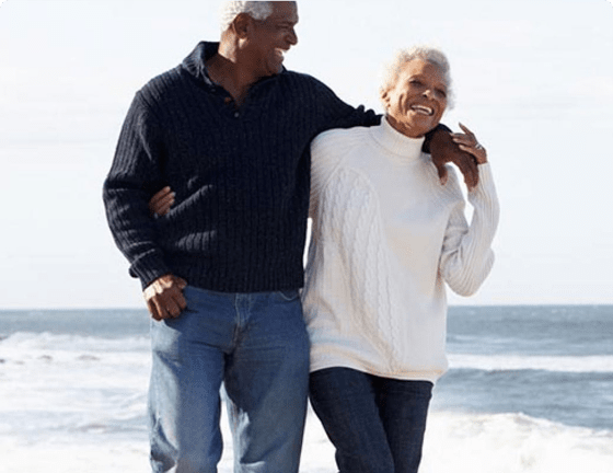 Elderly couple strolling along beach laughing together