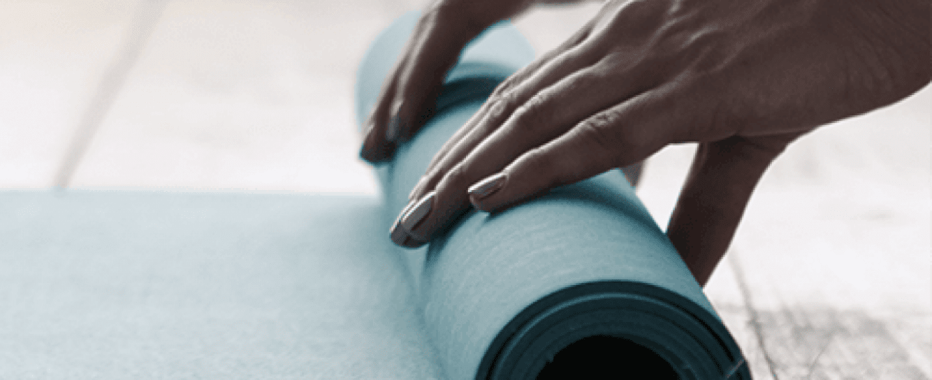 Hands rolling a yoga mat