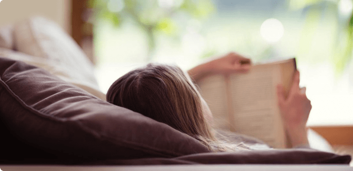 Woman reading a book whilst laying down