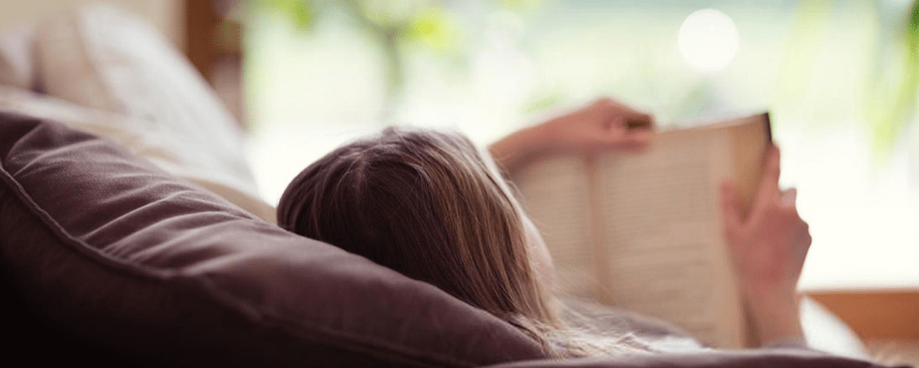 Woman reading a book whilst laying down